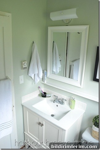 A small bathroom vanity area with a towel hanging on a hook above it.