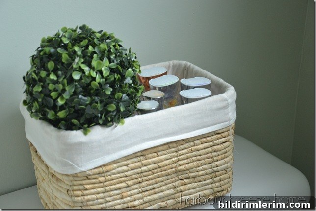 A lined wicker basket on the back of the toilet with lotion bottles in it.