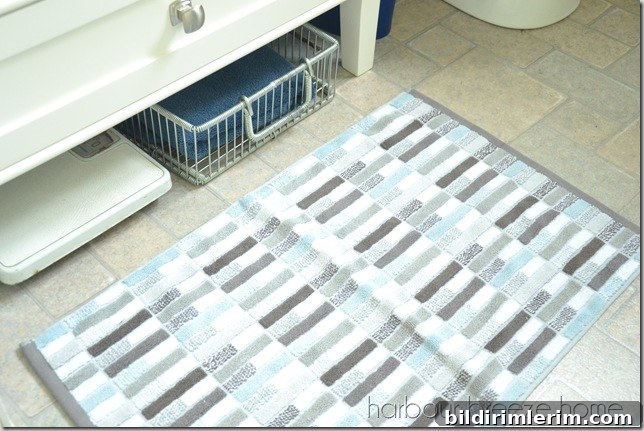 A weigh scale and a basket with towels tucked under a bathroom vanity.