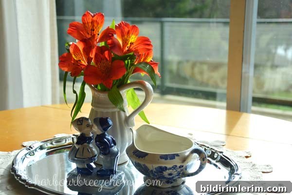 DIY Flower Arrangements Using Grocery Store Blooms 8 Orange flowers in a vase on a silver platter surrounded by blue print porcelin figurines