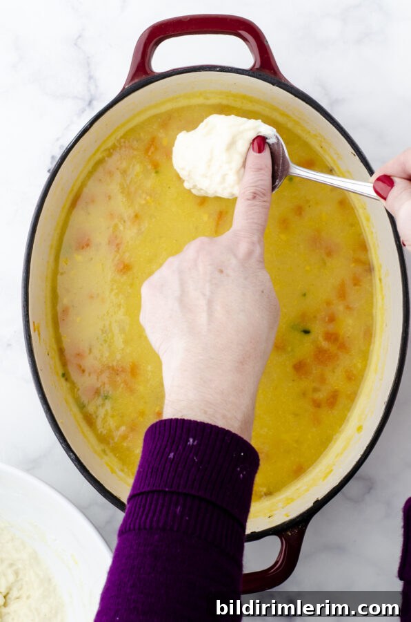 Drop dumplings being dropped onto the top of a pot of potato soup.