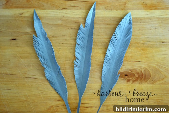 DIY Paper Feathers Tutorial: Handmade Feather Crafts 4 Paper feather shapes cut out of gray cardstock with tiny cuts around the edges to resemble the look of a feather.