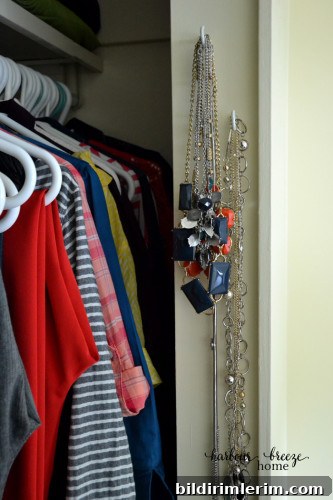 Small hooks in a doorway holding necklaces and belts.