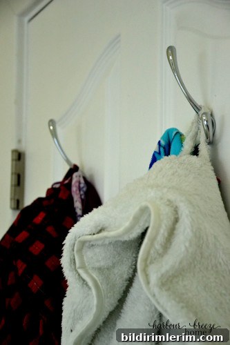 Hooks holding robes and accessories in a small bedroom.