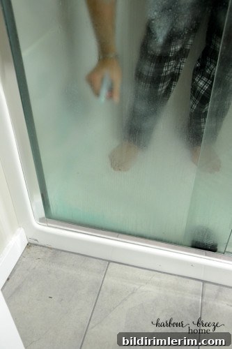 A man spraying on homemade shower door cleaner in a shower