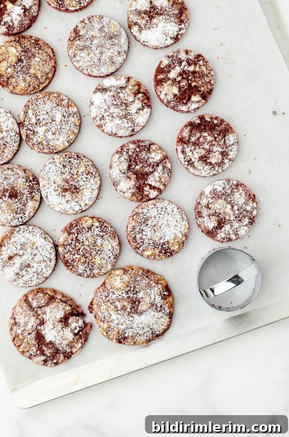 Red Velvet Cookies on a cookie sheet with most of them cut with a 3 inch cookie cutter.