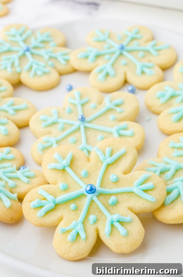 Platter of snowflake cookies made with Pillsbury sugar cookie dough decorated with blue icing and blue pearl sugar bead in the center