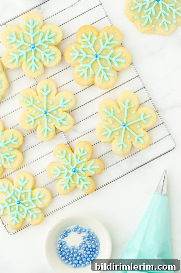 Close up of snowflake sugar cookies with blue frosting in a pastry bag.
