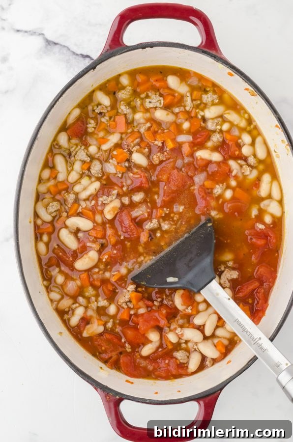 Spicy Buffalo Chicken Chili Recipe Inspired by Rachael Ray 6 All ingredients for Rachael Ray Buffalo Chicken Chili in a dutch oven being stirred together with a large spoon.