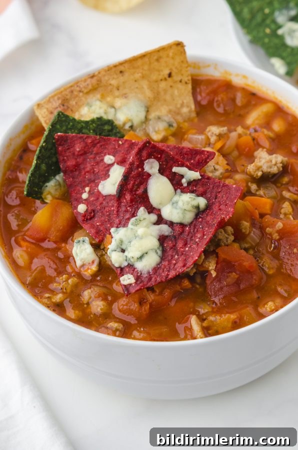 Spicy Buffalo Chicken Chili Recipe Inspired by Rachael Ray 8 Red tortilla chips with melted blue cheese sitting on top of a bowl of spicy buffalo chicken chili soup.