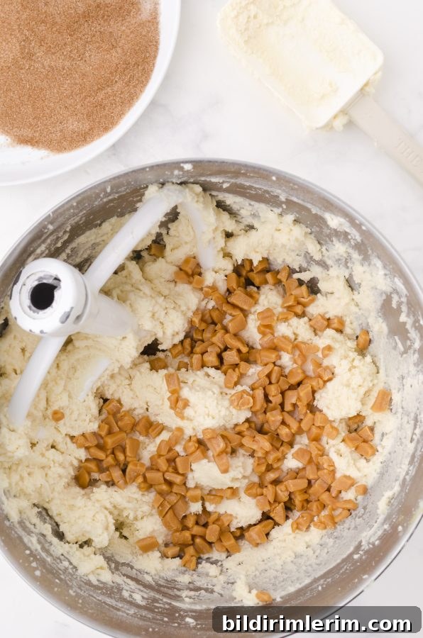caramel bits added into snickerdoodle cookie dough batter in a bowl