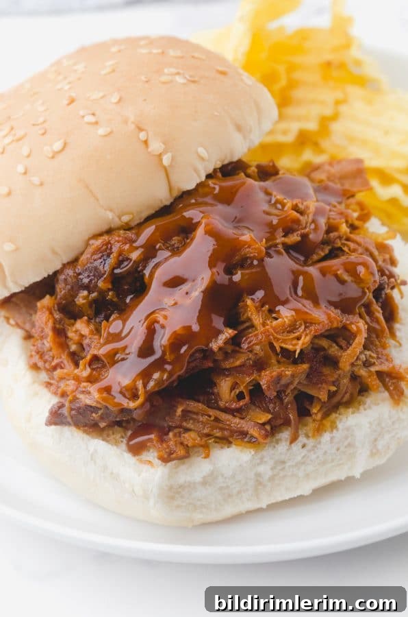 Crock Pot Pulled Pork Recipe: Tender, Juicy BBQ Flavor 2 Best Ever Crock pot pulled pork piled on a bun and topped with a drizzle of bbq sauce.