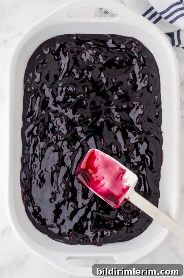Blueberry pie filling in the bottom of a white baking dish for blueberry dump cake.
