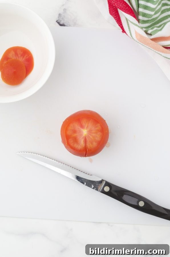 A small slice on the side of a tomato in preparation for deseeding it.