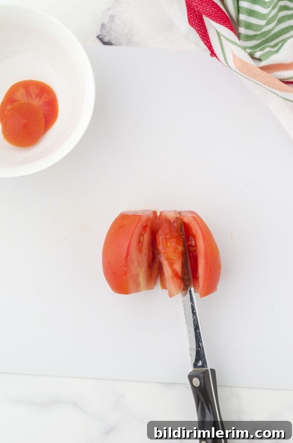 A knife cutting around the inner part of a tomato in order to deseed it.
