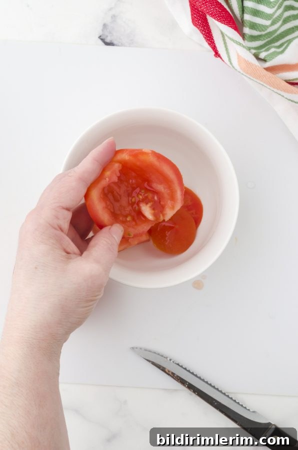 Scoop out the seedy area of the tomato area into a bowl (to dispose easily)