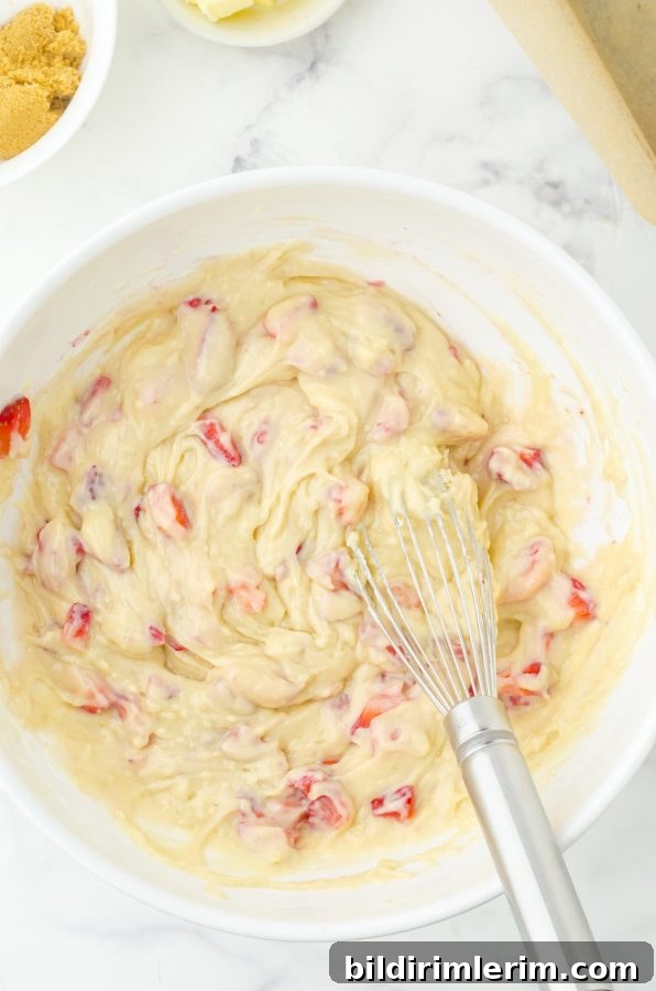 Fresh strawberries folded into quick bread batter in a medium sized bowl