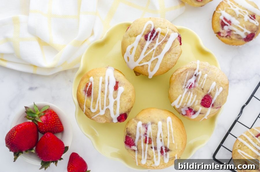 A yellow platter with strawberry muffins on it with a pile of fresh strawberries on the side.