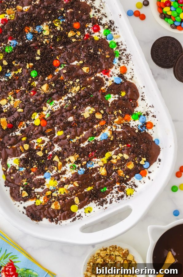 How to Make Oreo Ice Cream Cake with Oreo Crust 2 9x13 pan of ice cream cake with oreos, vanilla ice cream, hot fudge sauce and m&ms