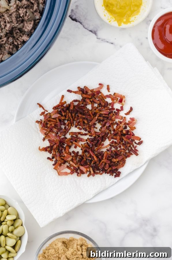 Crispy bacon bits sitting on a paper towel in preparation to be added to the crock pot for crock pot baked beans.