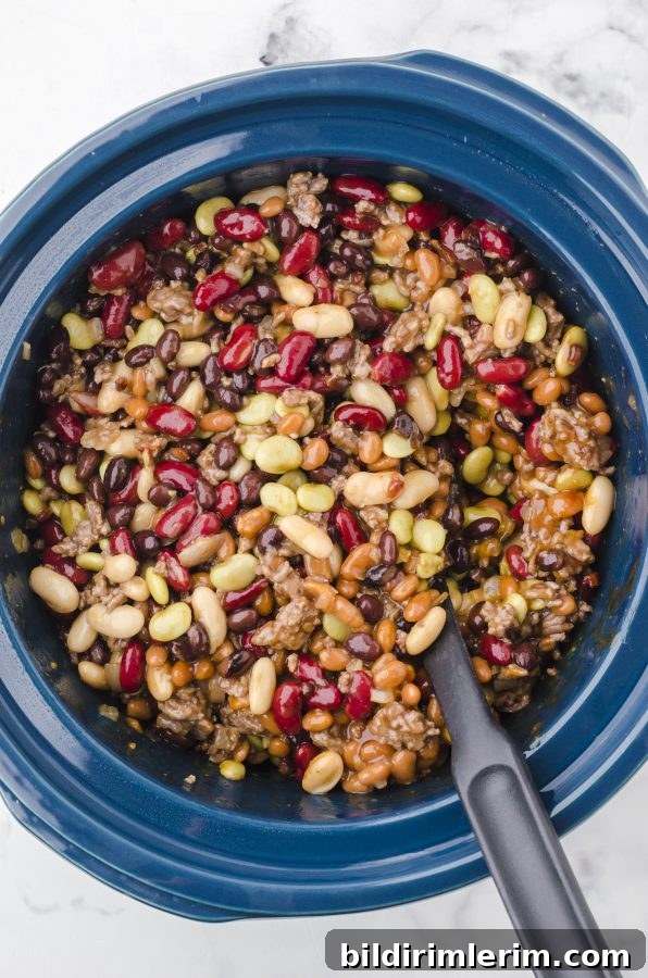 Ingredients for crock pot calico baked beans stirred together in a slow cooker.