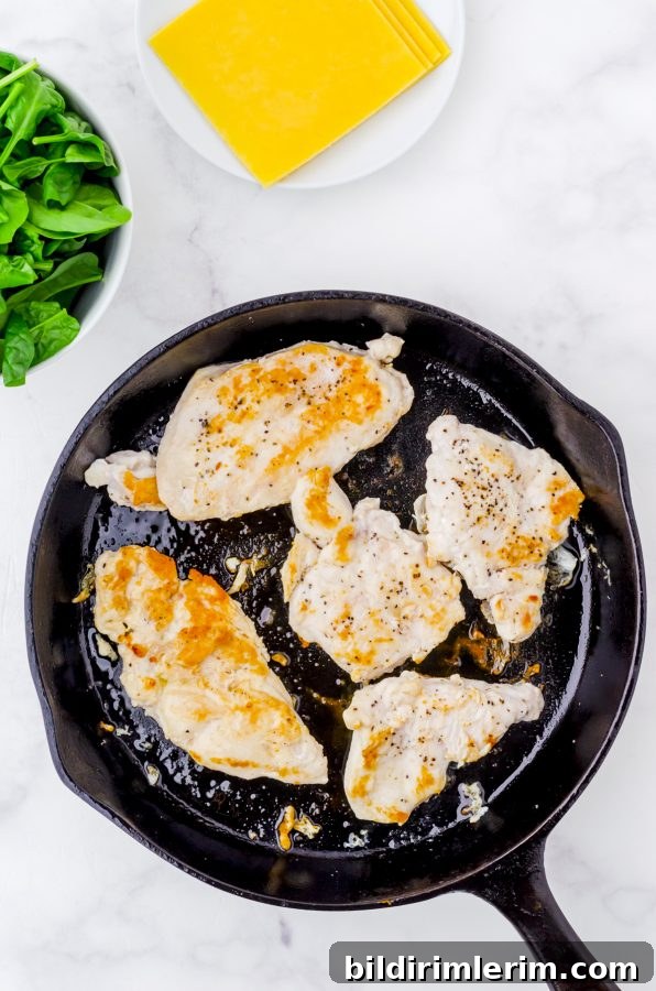 Chicken breasts browning in a cast iron pan.