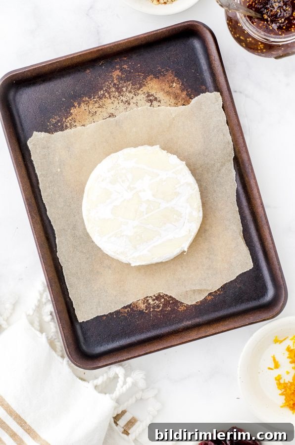 round of brie on a parchment lined baking sheet