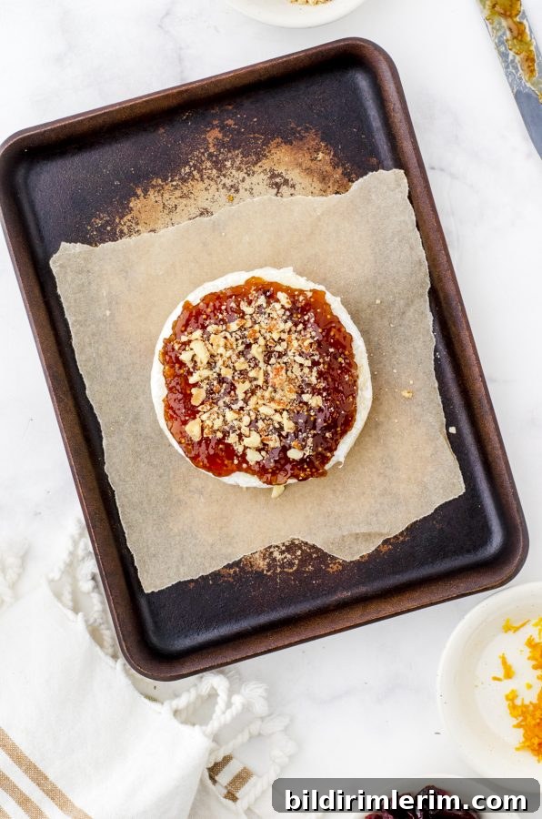 round of brie cheese with fig jam and nuts sprinkled on it