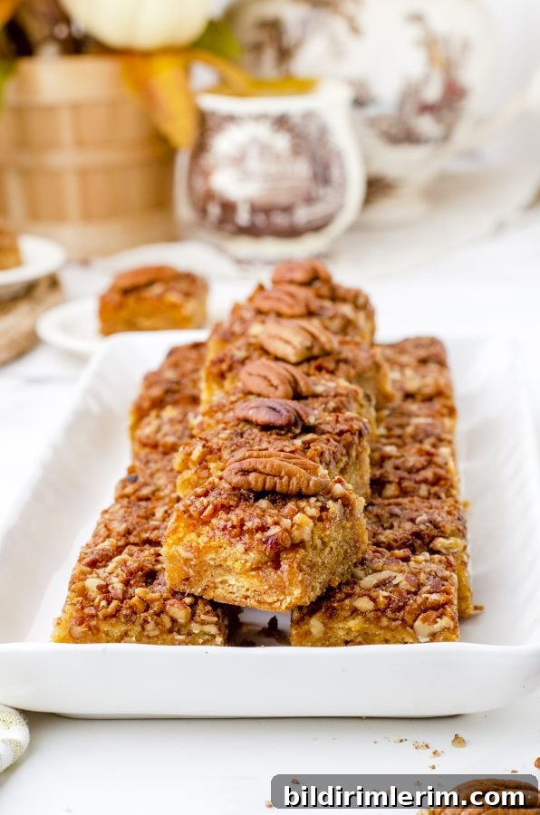 A platter of pecan pie bars stacked with pecan slices lining the tops.