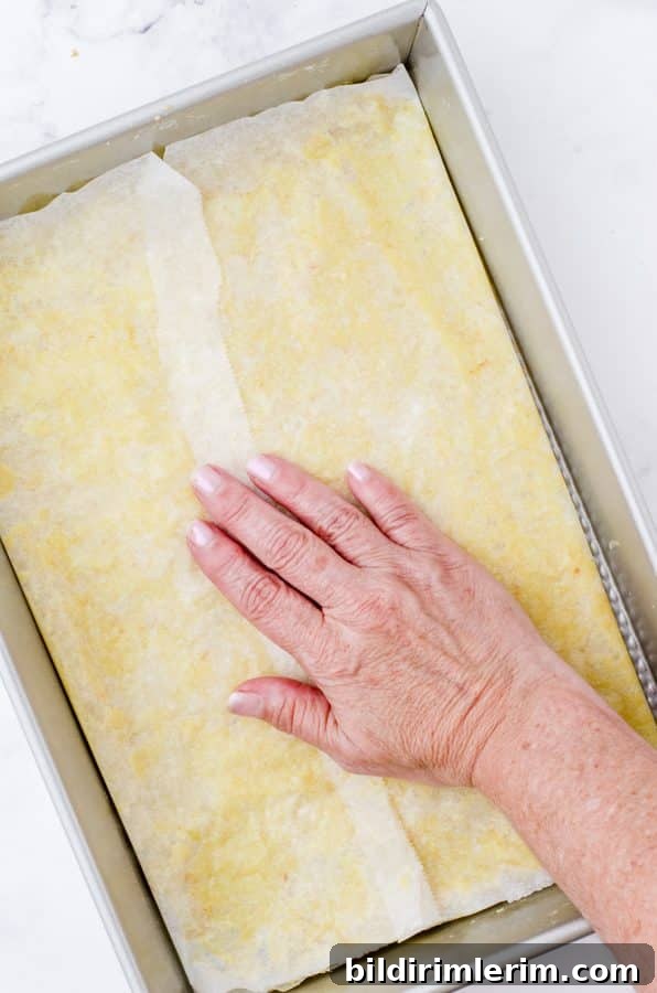 Pressing the pecan pie bar crust into the bottom of a baking pan