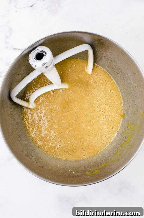 Pecan pie bar filling being mixed in the bowl of a stand mixer.