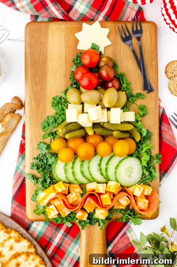 A charcuterie board arranged in the shape of a Christmas tree with meats, cheeses, and vegetables