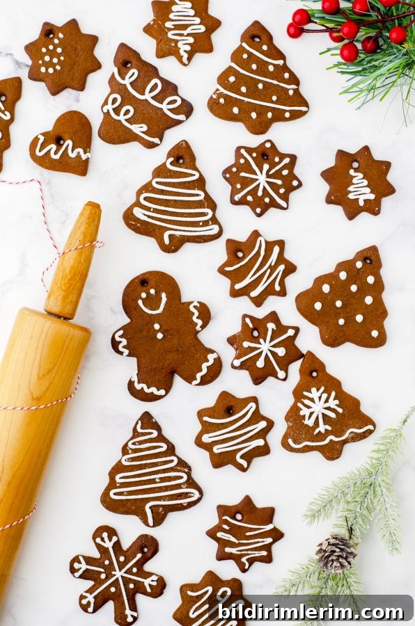 A variety of gingerbread cookies laying on a marble surface with a rolling pin beside.
