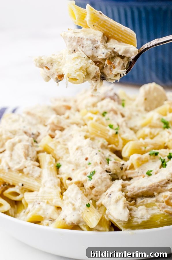 A fork full of crock pot chicken alfredo and pasta
