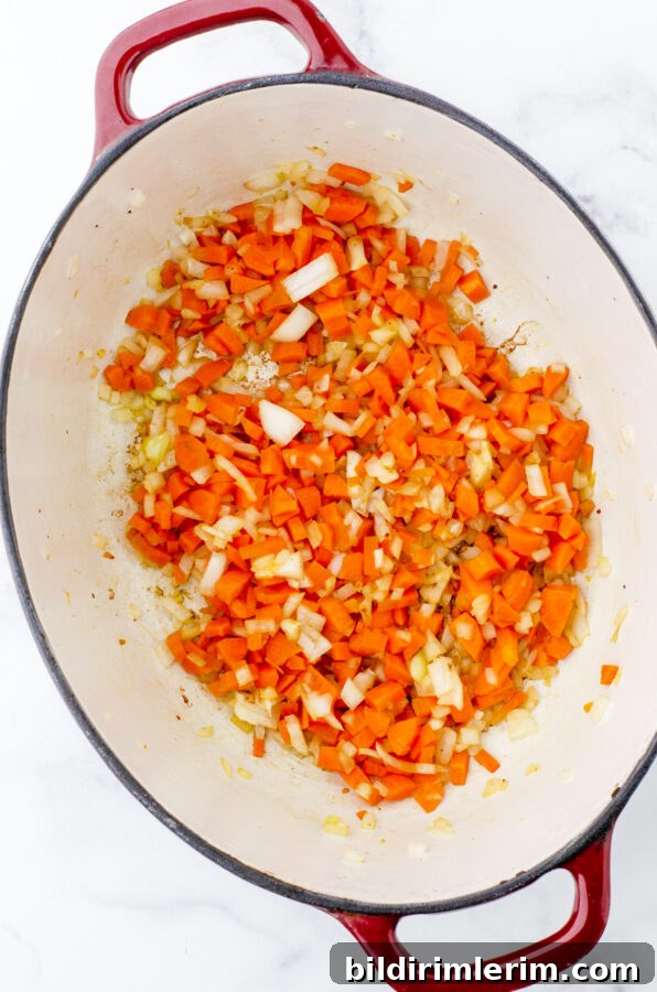 Diced carrots and onions in the bottom of a cast iron dutch oven.