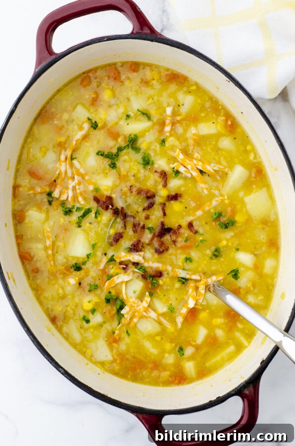 A pot of easy potato soup with chunky potatoes, corn, bacon bits, and shredded cheese.