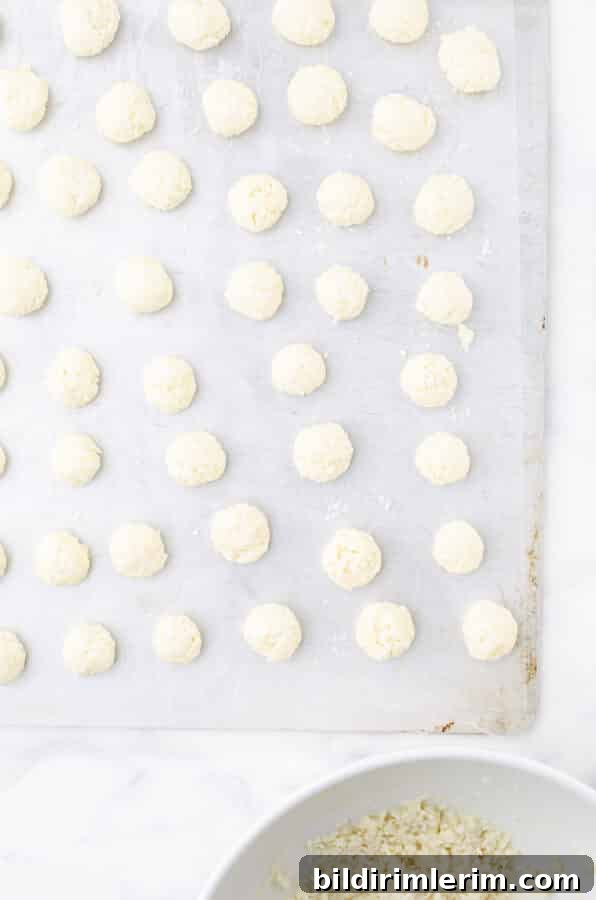 No-Bake Coconut Bliss Balls Recipe 4 No bake coconut balls on a parchment paper lined cookie sheet