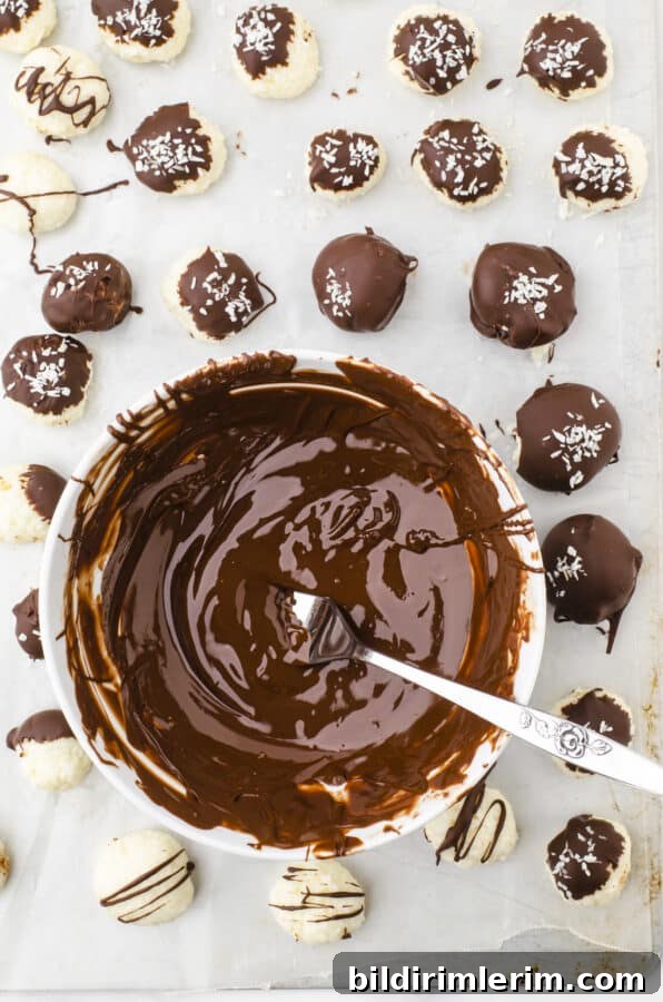 No-Bake Coconut Bliss Balls Recipe 5 Coconut balls no bake recipe being dipped in a bowl of melted chocolate