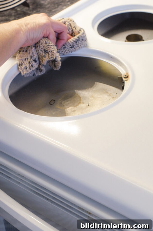 A woman cleaning the top of an electric stovetop