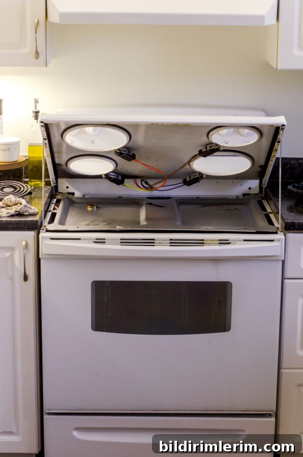 An electric stovetop with the top lifted up.