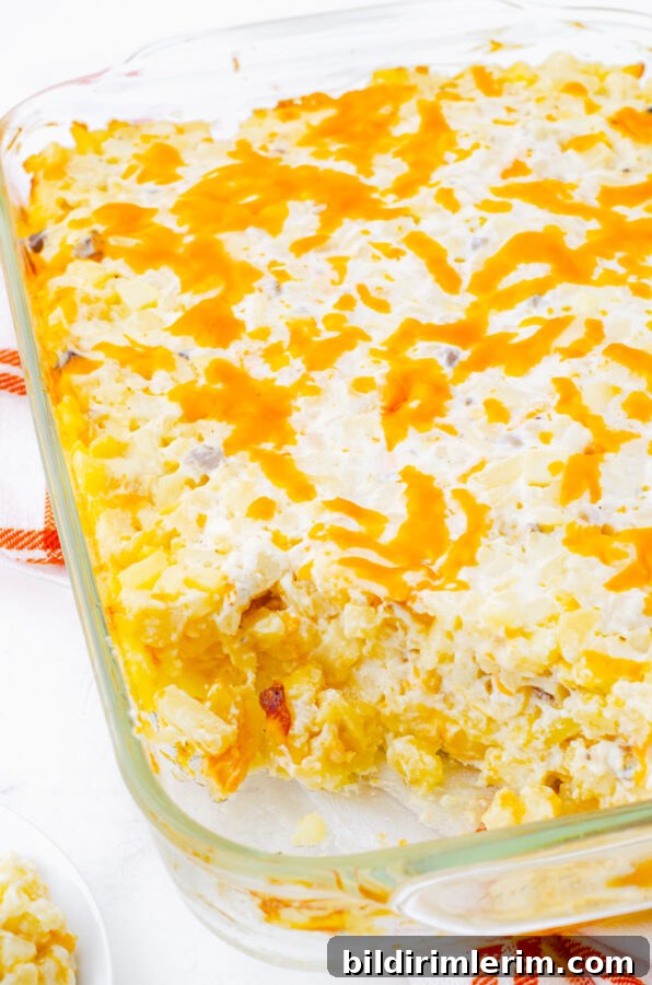 Creamy Cheesy Hash Brown Potato Casserole Recipe 7 Baked cheesy potatoes casserole with hashbrowns with a serving dished out of the casserole dish.