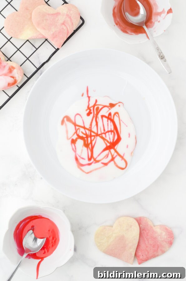A bowl of white icing with squiggles of the colored icing drizzled randomly on the top.