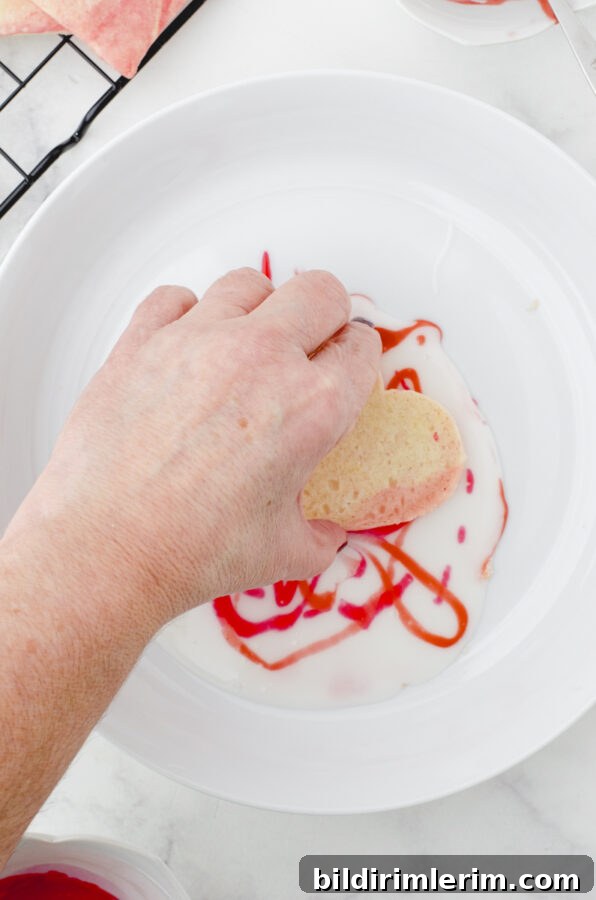 a woman dipping a cookie into the icing with drizzles on it.