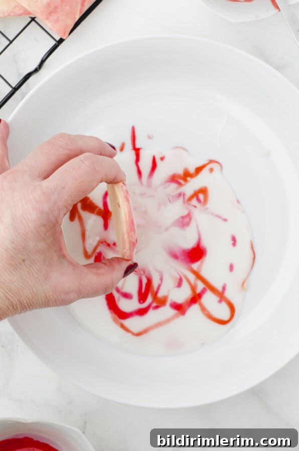 a woman pulling a cookie up and out of the icing