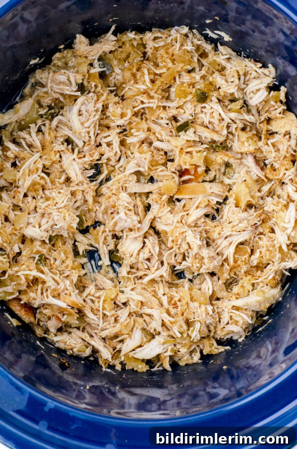 Shredded chicken in a crock pot mixed with the juices.