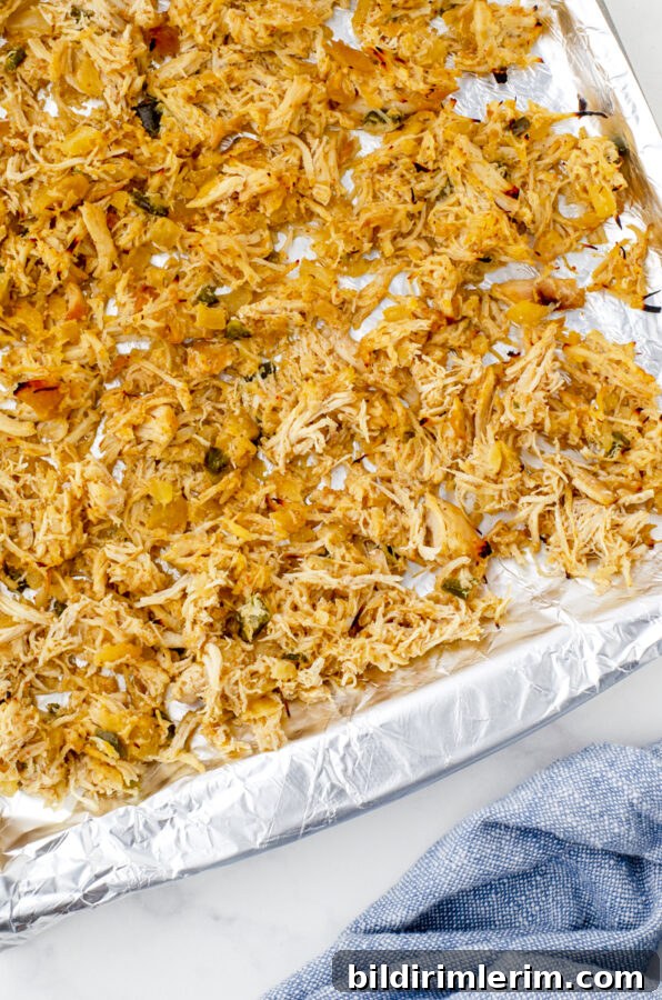 close up of shredded chicken after it has been under the broiler and is lightly charred on the edges.