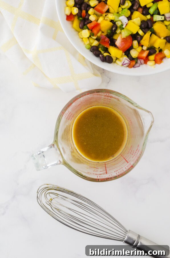 Mango salad dressing whisked together in a large measuring cup that pours.