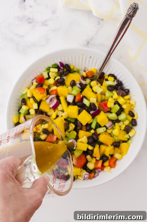 Mango salad dressing being poured on a bowl of mango salad.