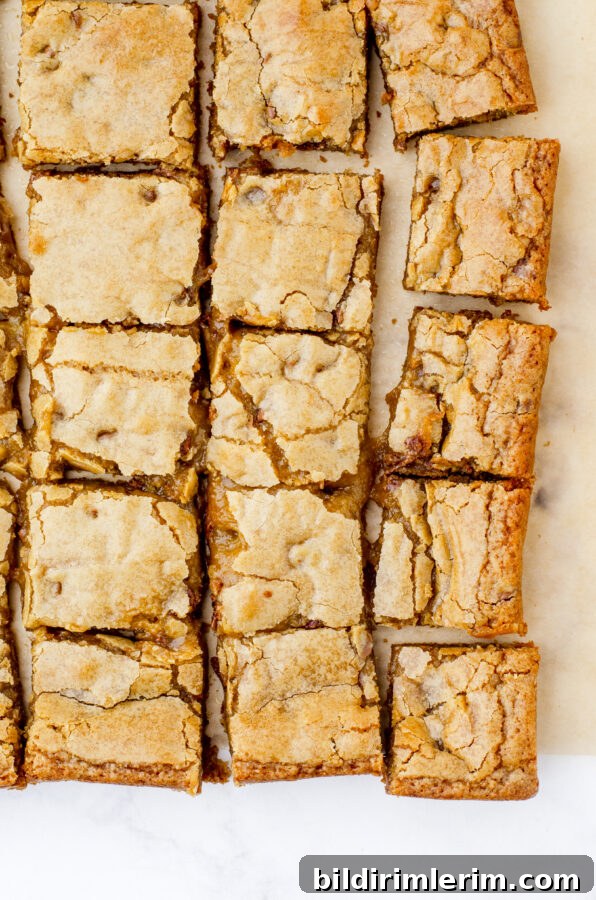 Soft, Chewy Butterscotch Blondies Recipe 2 Butterscotch brownies cut and laying on a piece of parchment paper.