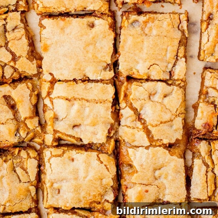 Butterscoth brownies recipe - otherwise known as blondies - cut in squares and sitting on parchment paper